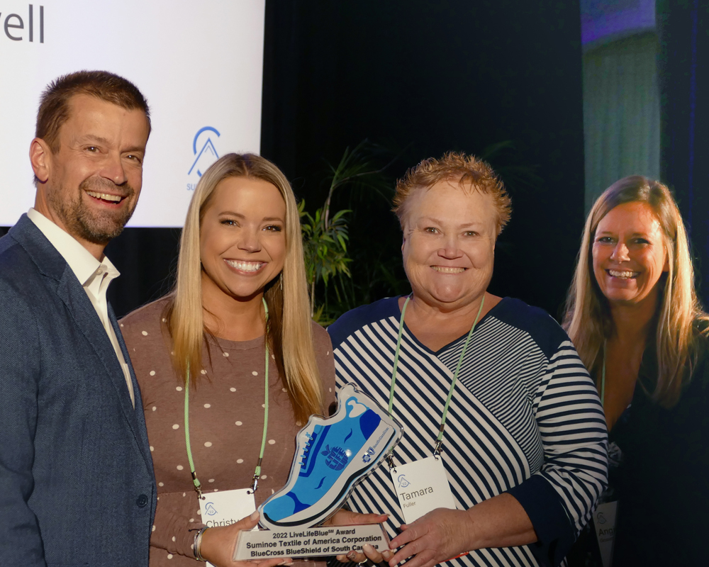 four people holding blue shoe award smiling