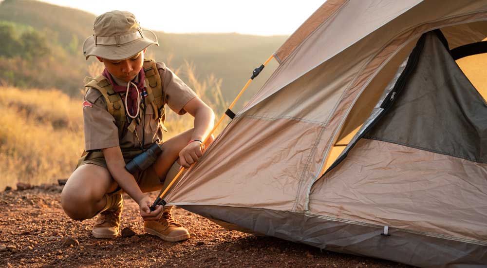 young boy kneeling by tent