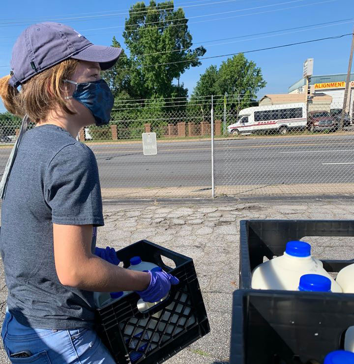 woman helps load gallons of milk at Harvest Hope Food Bank