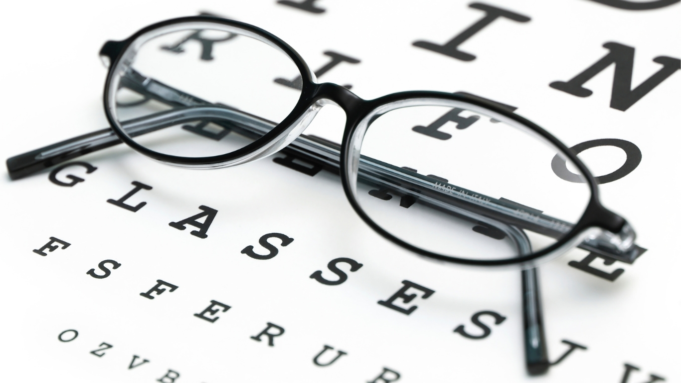 Glasses resting on an eye chart, symbolizing vision testing and eye care.