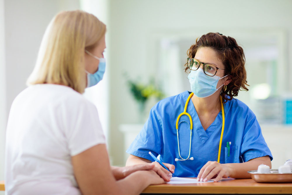 doctor wearing mask talking with patient at table