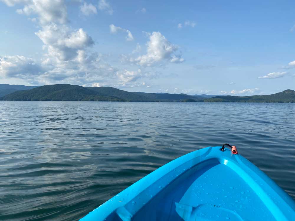 front of kayak on lake with mountains and blue sky