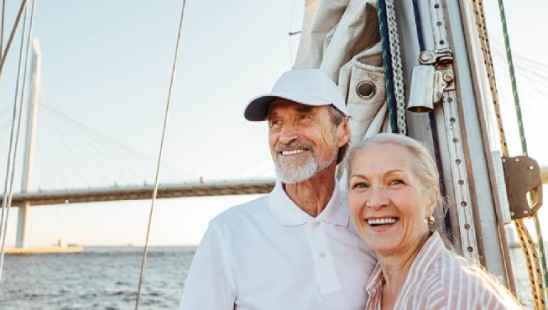 Man and woman on a sailboat in front of a bridge