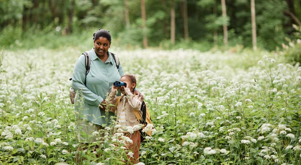 woman and child in field holding binoculars