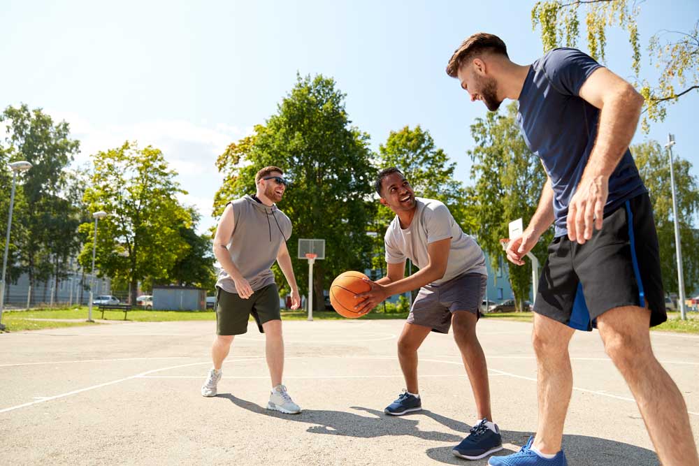 Three men playing basketball on outdoor court