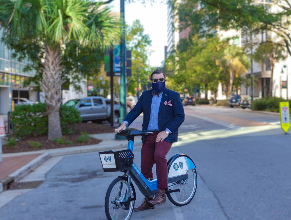 Man wears a mask while riding a blue bike