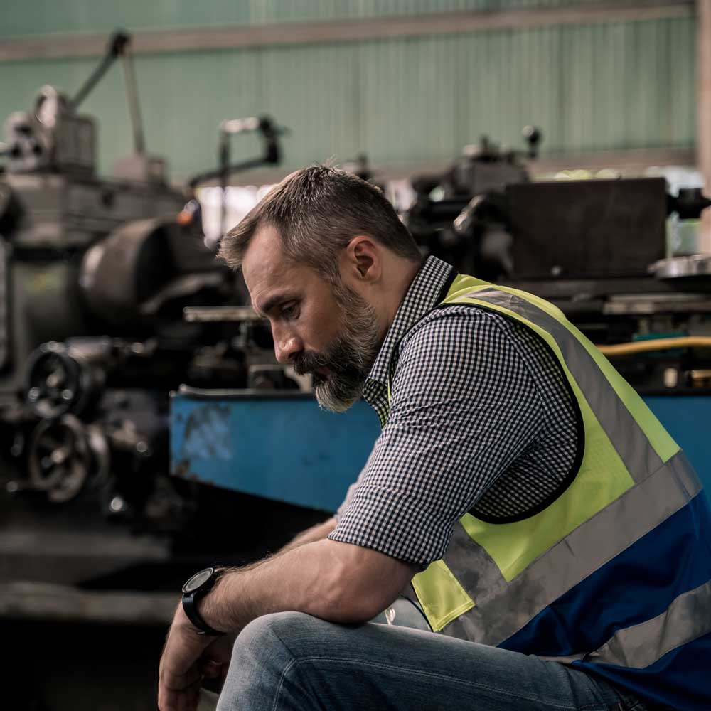 man in vest looks distraught in factory