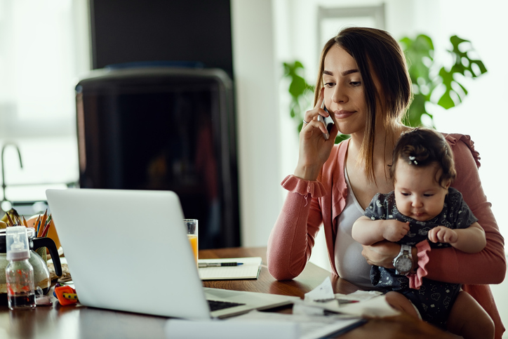 woman holds baby in lap and talks on phone