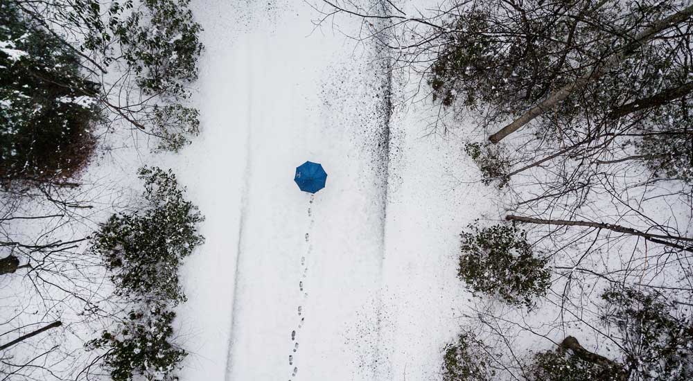 person walking in snow with blue umbrella 