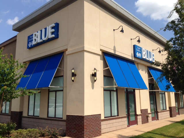 tan building with blue awnings and Blue retail signs