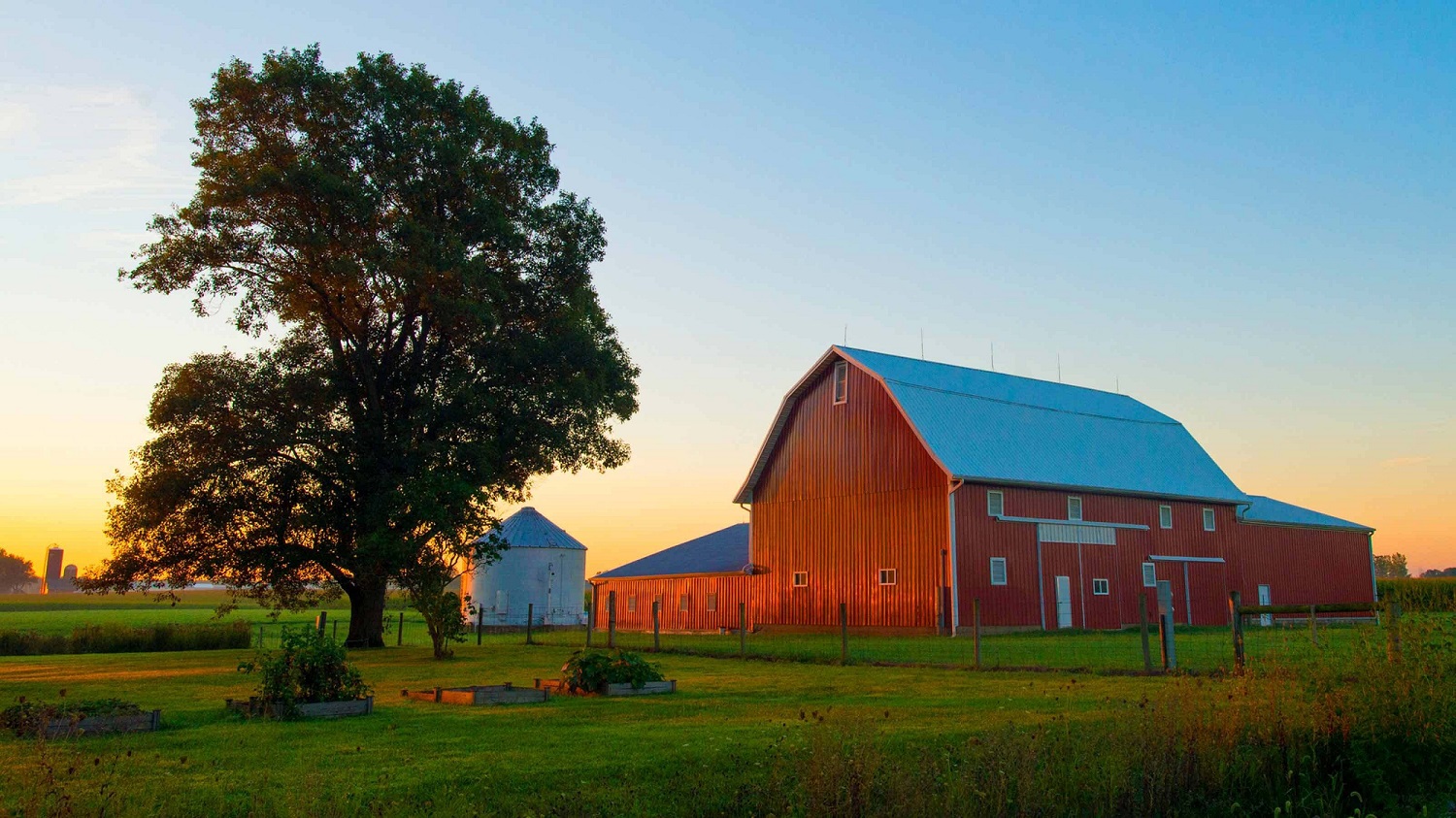 large red barn on farm with trees and blue sky