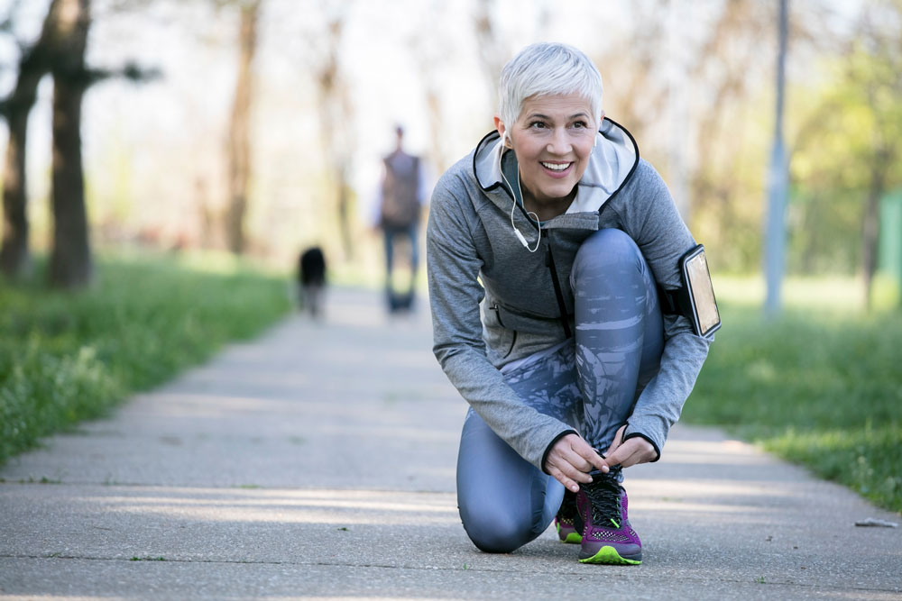 elderly woman ties her shoe outside