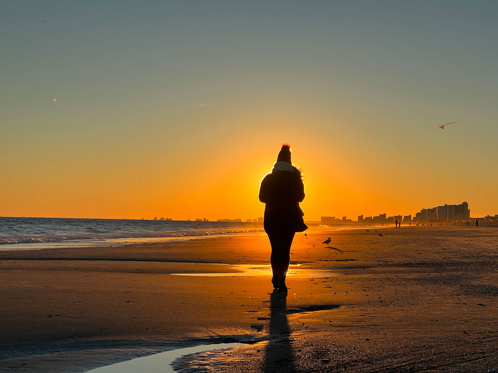 person walking on beach with sunset