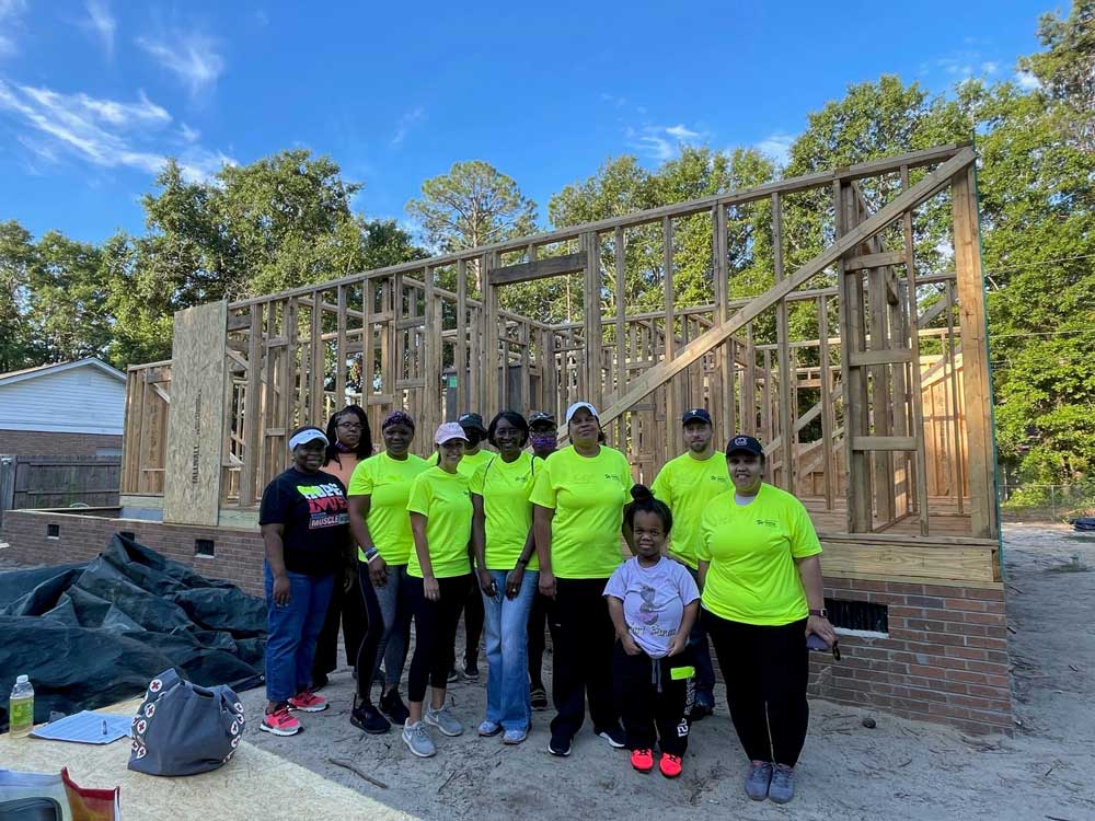 group of volunteers in front of house frame