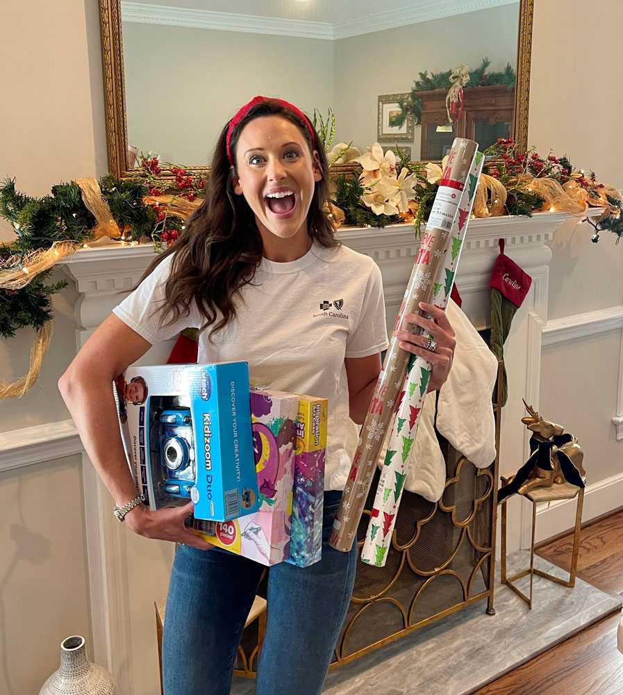 BlueCross employee smiles with gifts and wrapping paper