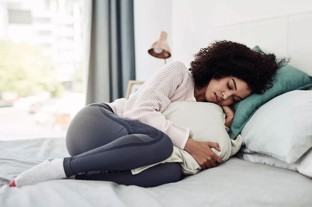 woman curled up around pillow looking sad