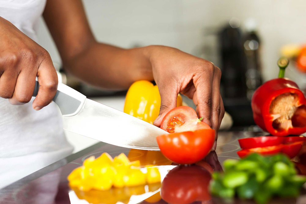 A person uses a knife to prepare fresh vegetables in a kitchen.