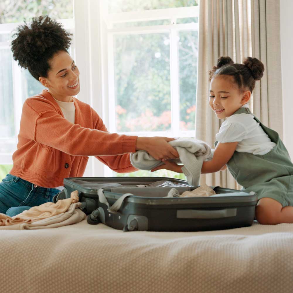 woman and girl on bed packing suitcase