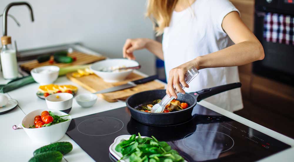 woman cooking fresh vegetables on stove