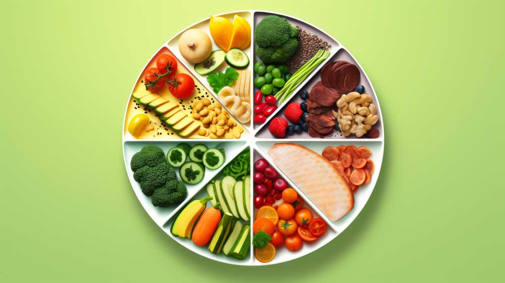 Plate with dividers and rainbow of fruits and vegetables on green background