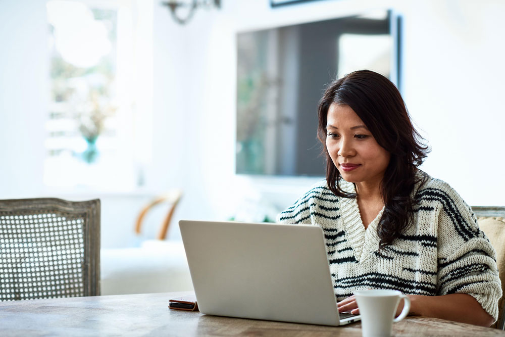 woman sitting at table with laptop and coffee cup