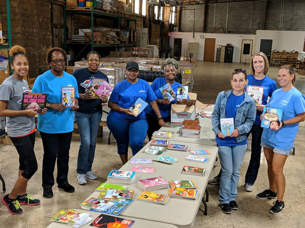 group of employees holding books at book drive