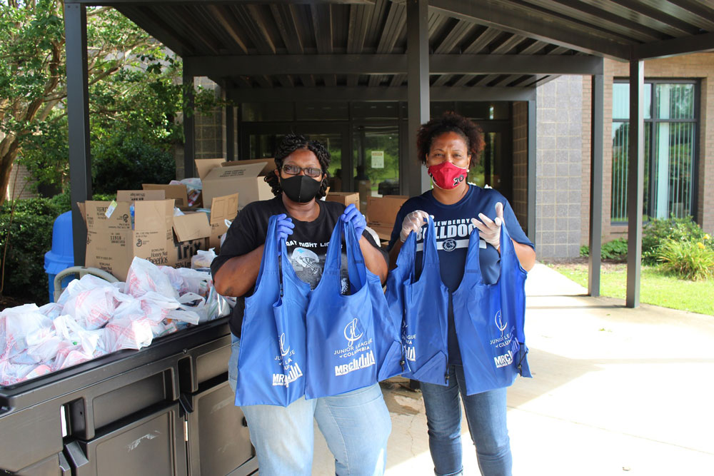 two women holding bags of supplies at united way event