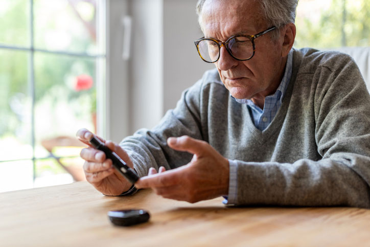 Elderly man takes blood sugar with meter