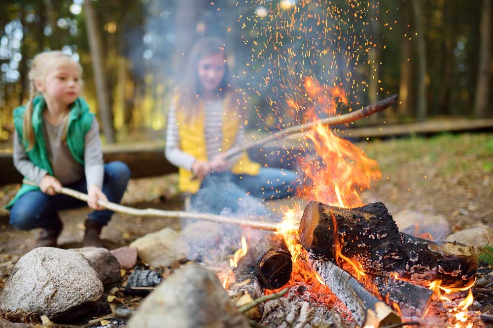 two girls beside fire with sticks